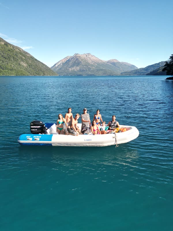 El grupo a bordo de la lancha, con el lago turquesa y un cerro nevado de fondo