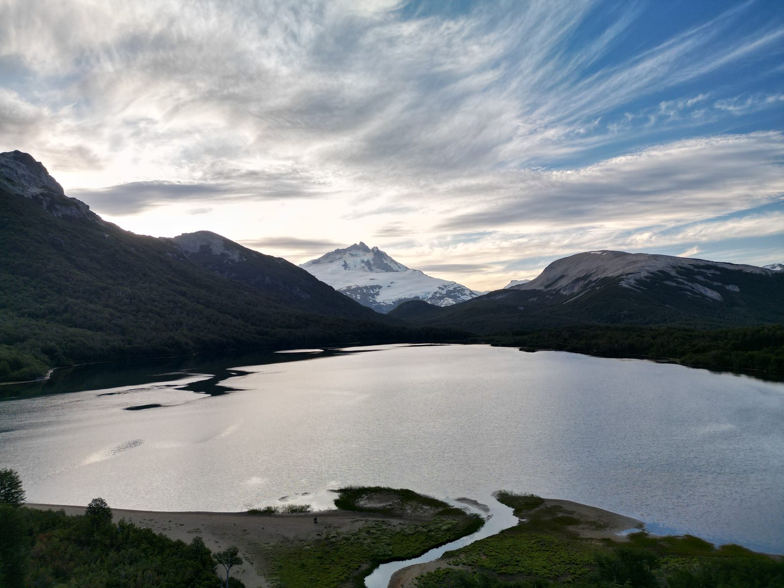 Laguna escondida al pie de la cordillera con un cerro nevado de fondo