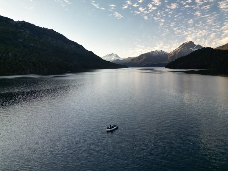 Lago y cordillera al atardecer con una lancha