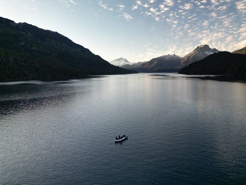 La lancha sola en el lago al caer la tarde, con cerros nevados al fondo