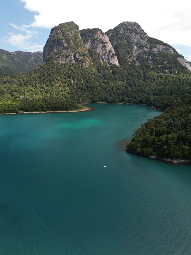 Paredones de granito sobre el lago turquesa, con la lancha en el centro