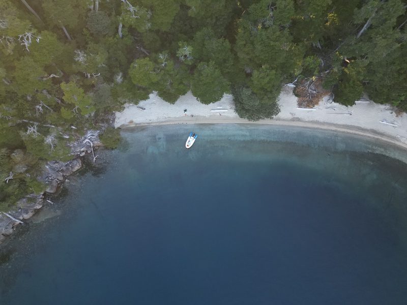 Vista aérea con dron de una playa escondida con la lancha fondeada
