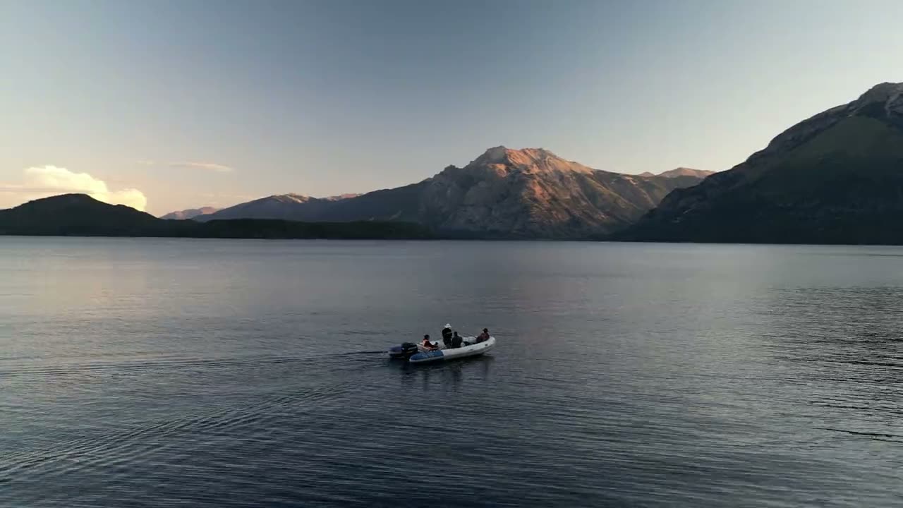 La lancha navegando el lago al atardecer, con la cordillera de fondo