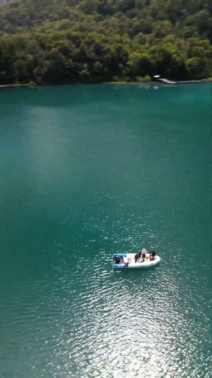 Vista con dron de la lancha sobre agua turquesa, subiendo hacia los cerros